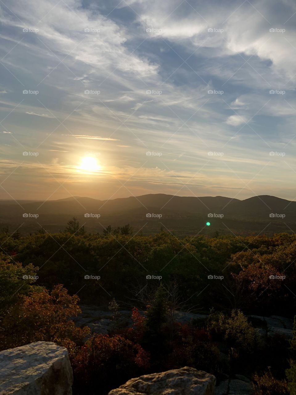 Hazy sunset on the horizon with scenic view of mountains and forest in Autumn, atop Mount Battie in Camden, Maine USA 