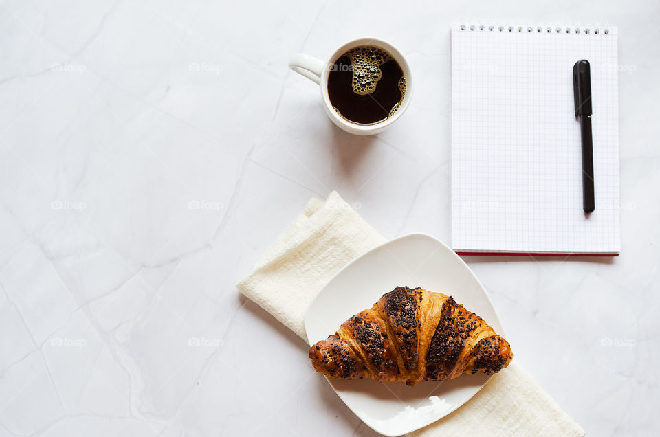 Business working morning with cup of hot coffee, sweet croissants, pen, notebook on white background close up. Top view, copy space, flat lay, mockup.