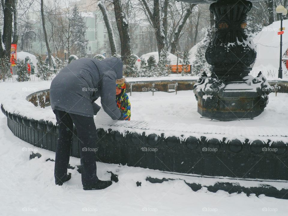 a man with a child makes a snowman