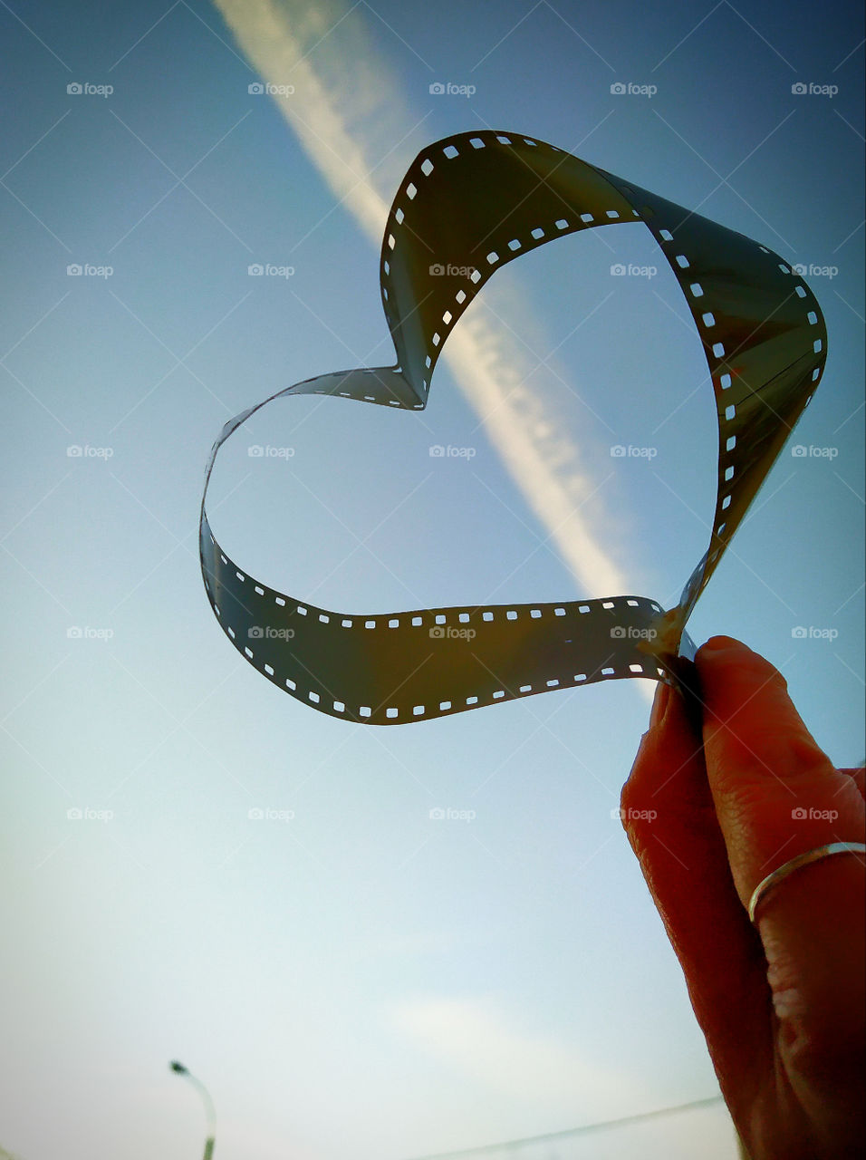 Film for photography in the shape of a heart against the sky with clouds