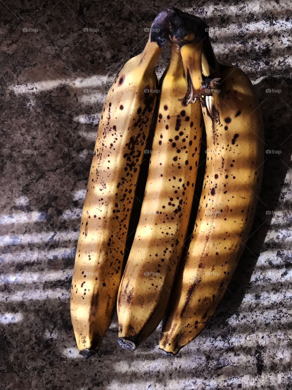 Three fresh ripe bananas in light and shadows 