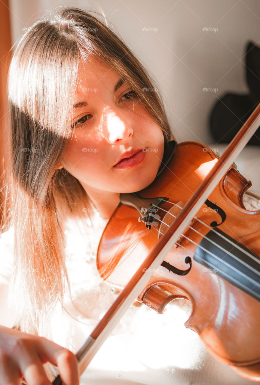 A girl play the violin in the house