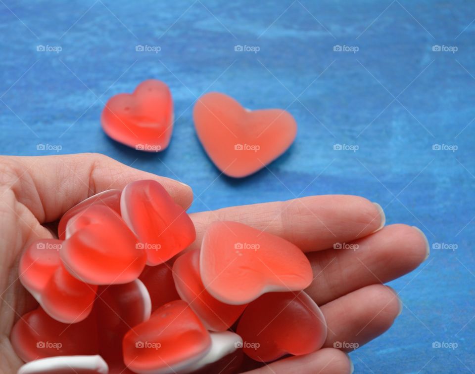 jelly beans hearts in hand blue background