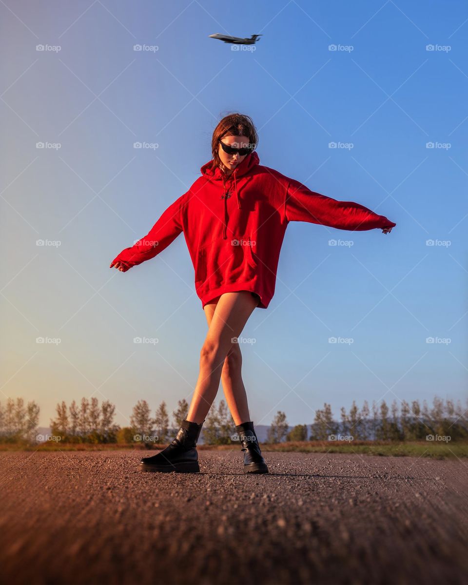 Girl on old abandoned airfield with private jet flying above her head 