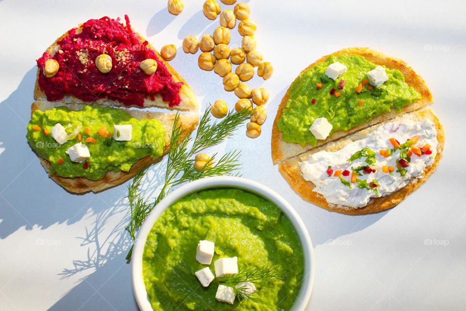 Top view of slices of bread with three types of spread: beetroot  with humus,  pea spread and cream cheese with vegetables