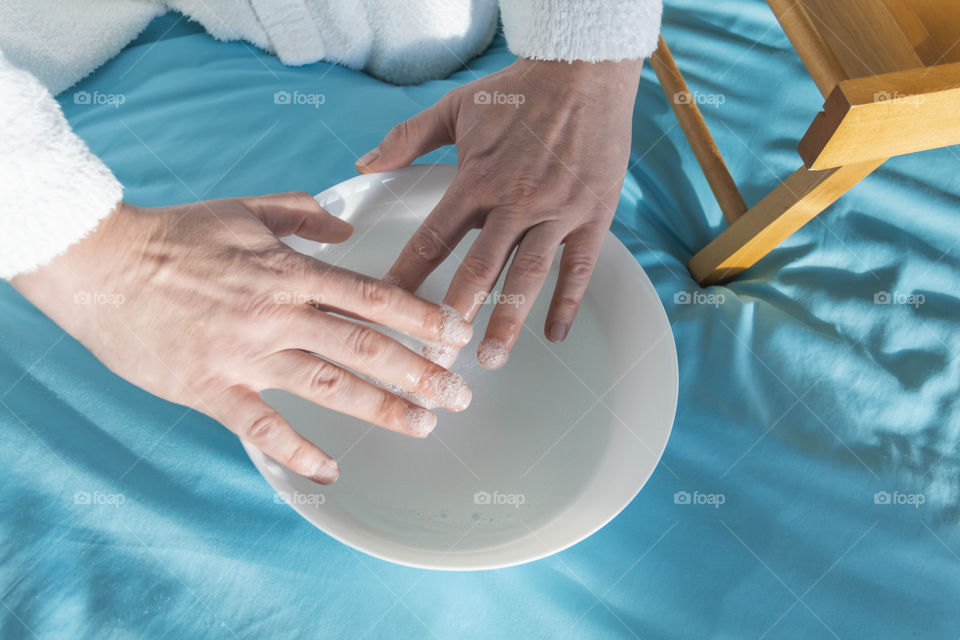 A man at home takes care of himself and does a manicure at home on a blue background and with orange.