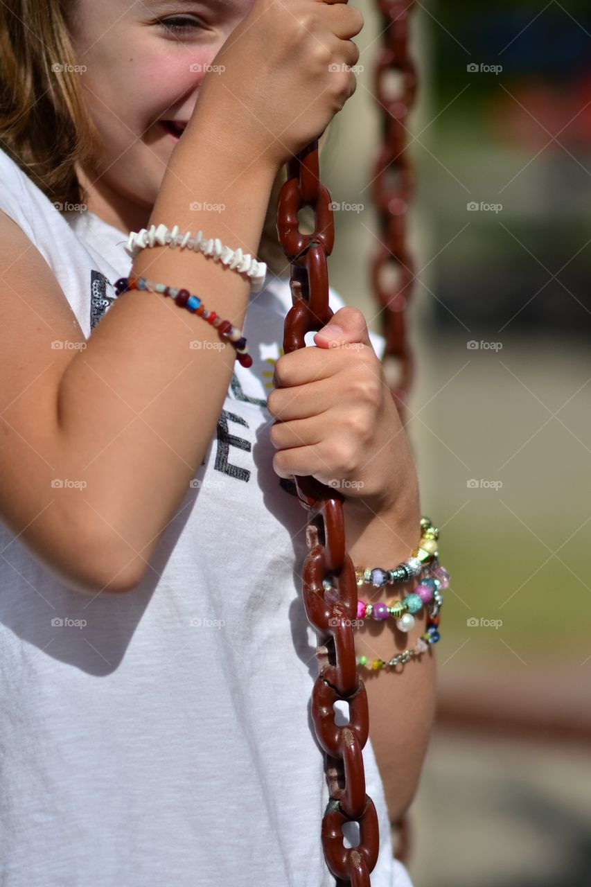 Young girl swinging on a chain in the playground. 