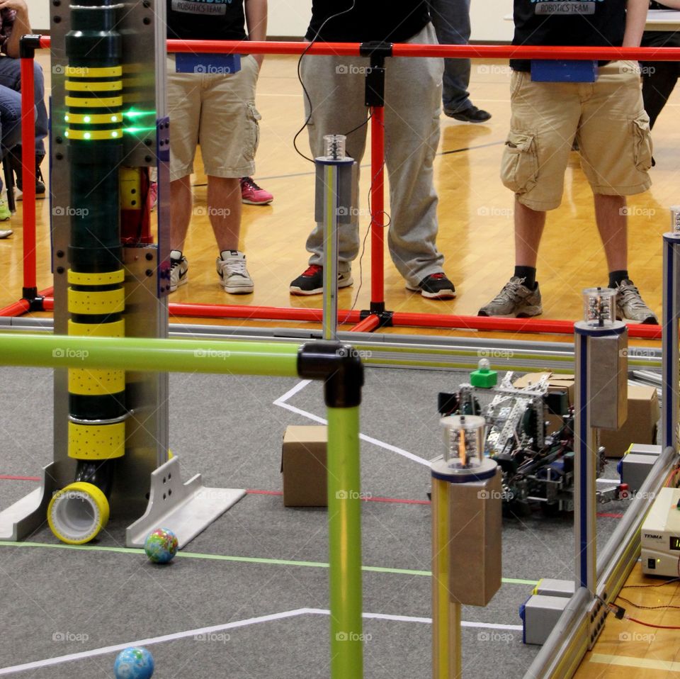 A team of 3 people control a robot performing tasks in a robotics competition 