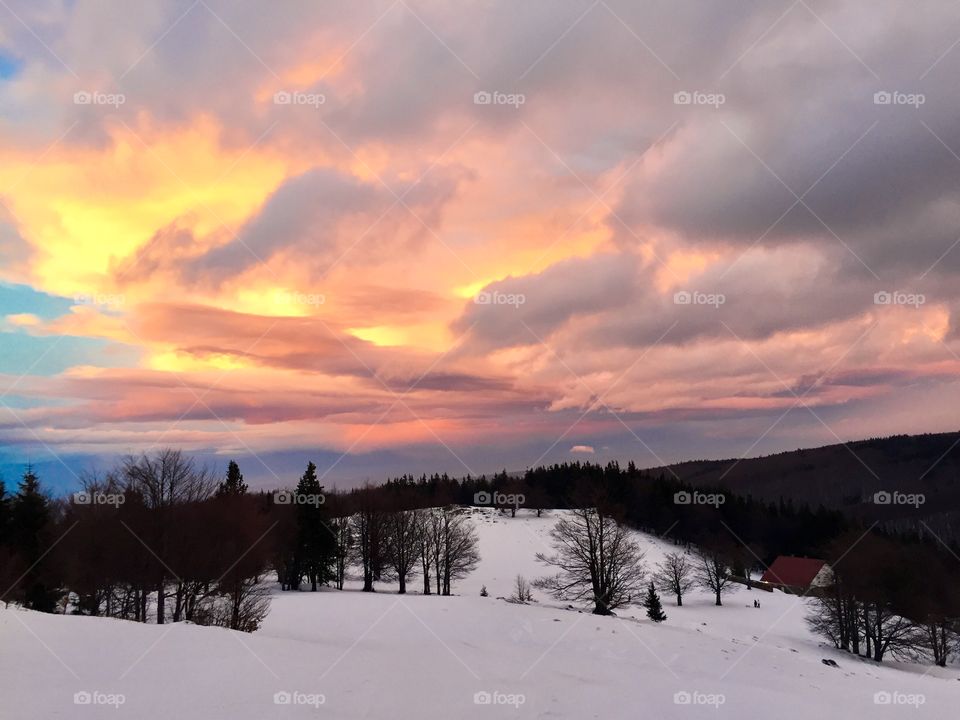 Beautiful sunset in winter over a chalet surrounded by forest