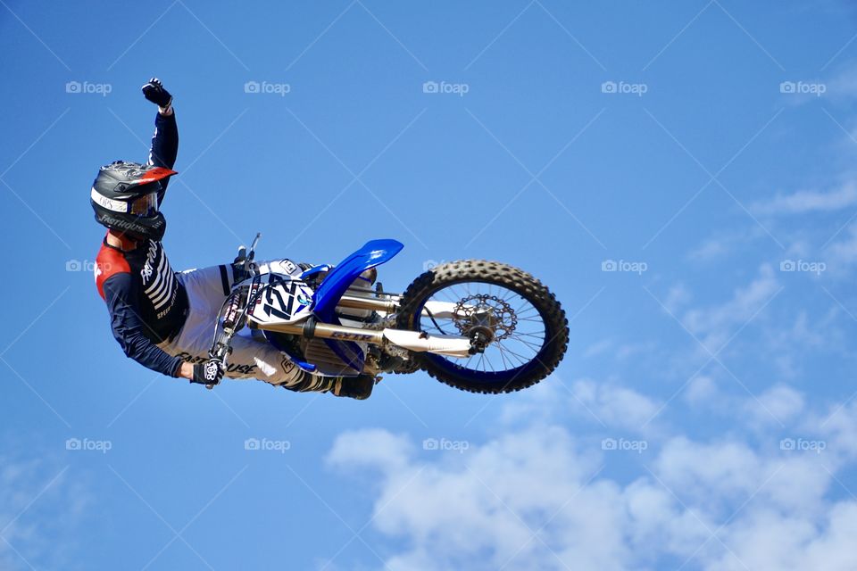 Motocrosser displaying a victory salute upon winning the race flying sideways