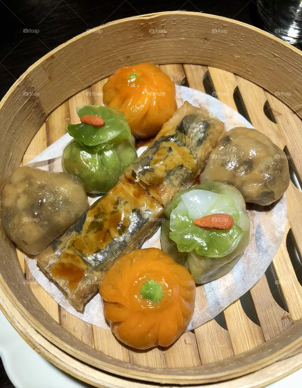Assorted dim sum dumplings inside bamboo steamer basket, orange and green dumplings, Chinese cuisine, Cantonese cuisine 