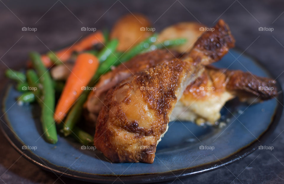 roasted chicken legs served with roasted carrots and green beans on a blue plate