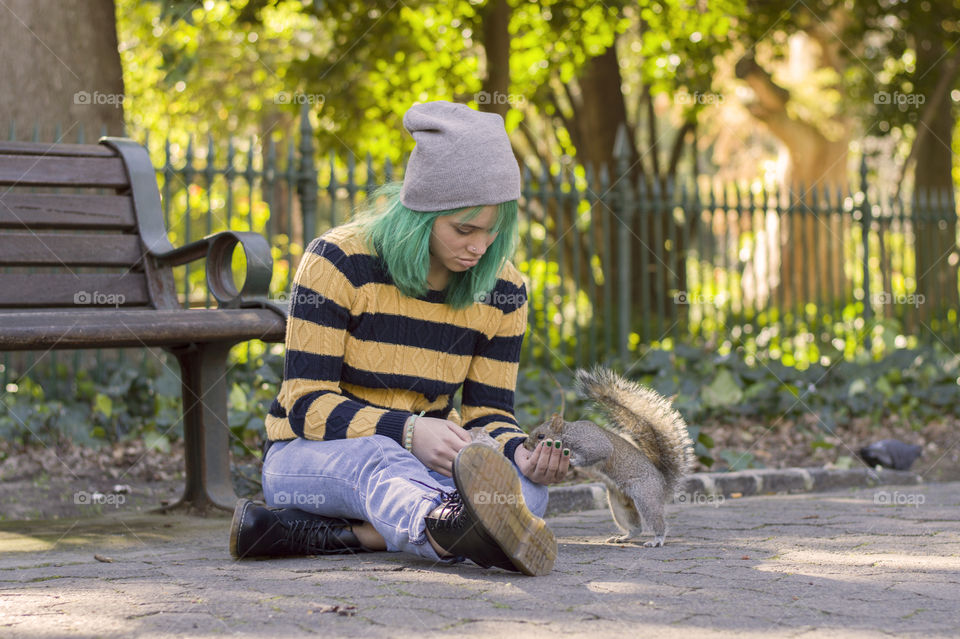 Alternative girl with green hair feeding a squirrel