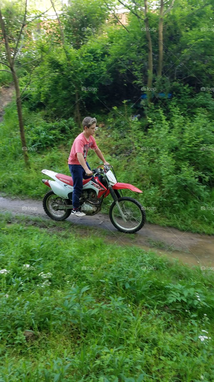 Boy ridding motor bike on dirt road