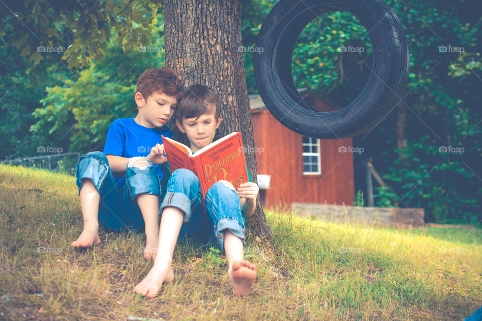 Two Boys Leaned Against a Tree Reading a Book