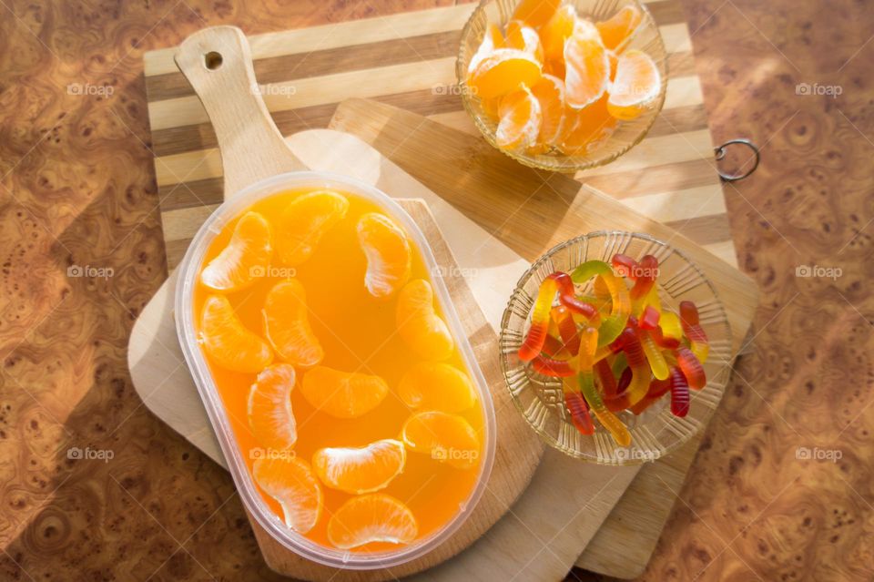 Delicious orange jelly with tangerine slices in a container and jelly worms.