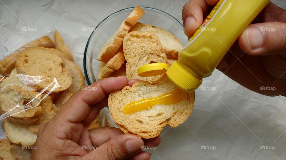 Mãos preparado Torradinhas, (fatias torradas de pão francês) com mostarda. 1/6