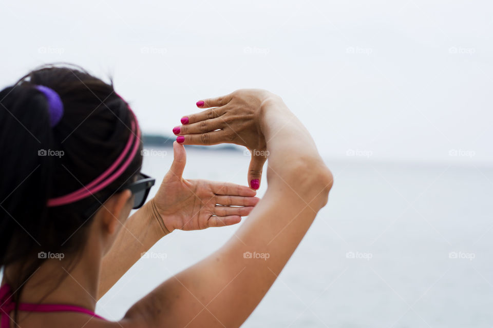 viewfinder shape. woman on beach making viewfinder shape out of hands