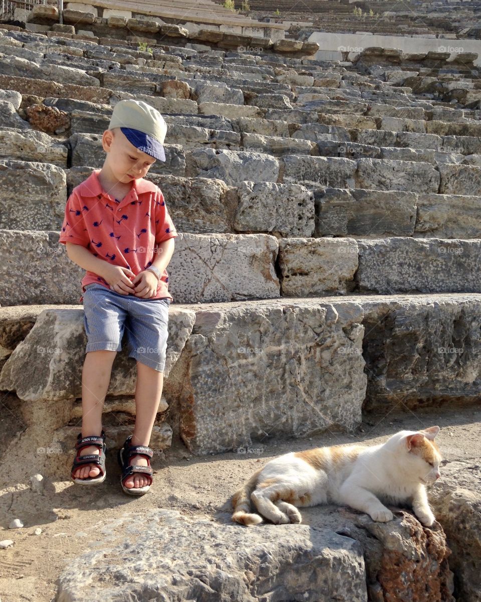 Little boy and cat on the steps of an ancient amphitheater