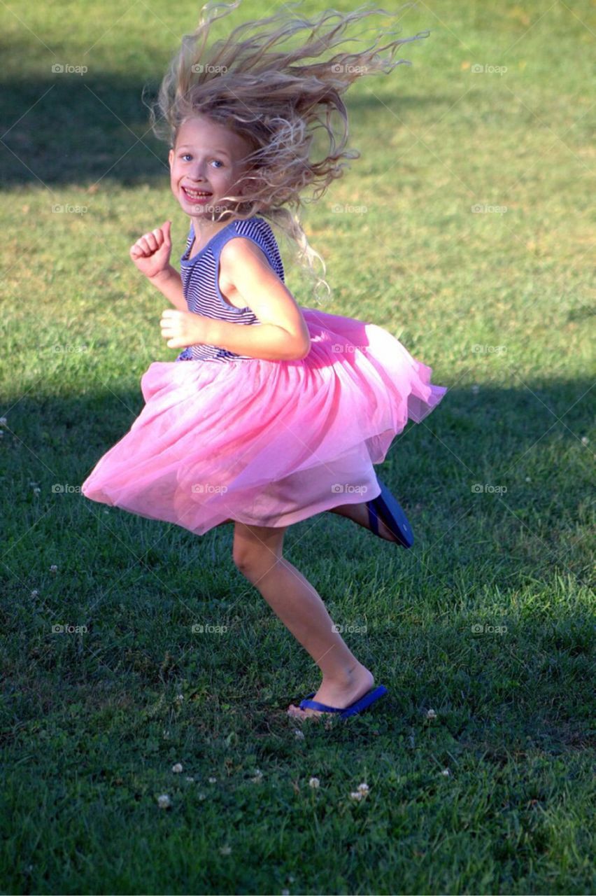 Young girl running on grassy field