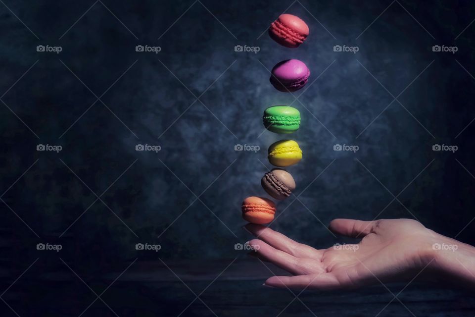 Multicolored macarons fly into the hand