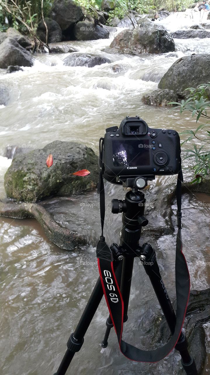 camera set up on tripod for long exposure photography of a river in the forest