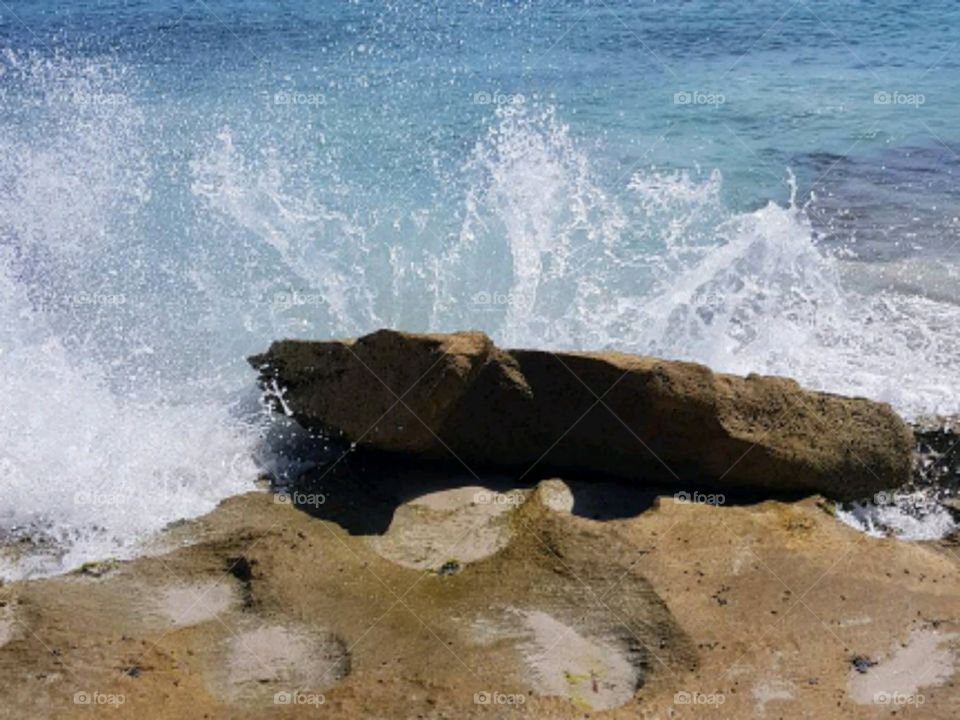 Beach water splash against rock
