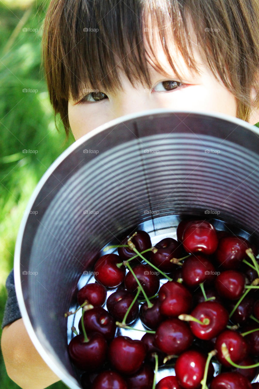 Boy holding cherries in container
