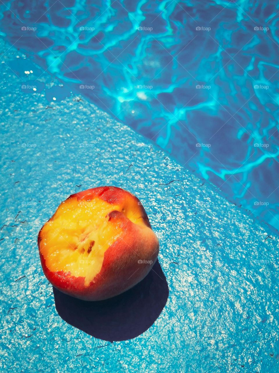 Bitten peach on a blue pool in summer