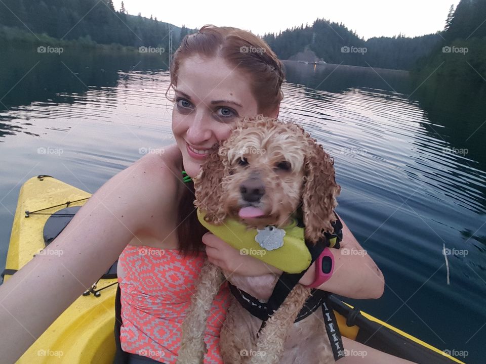 Happy woman sitting in kayak with dog on lake