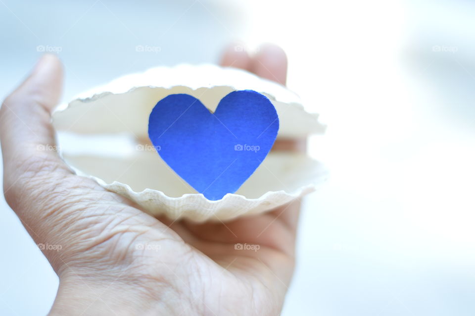 Blue colored heart in snow white colored pearl shell.