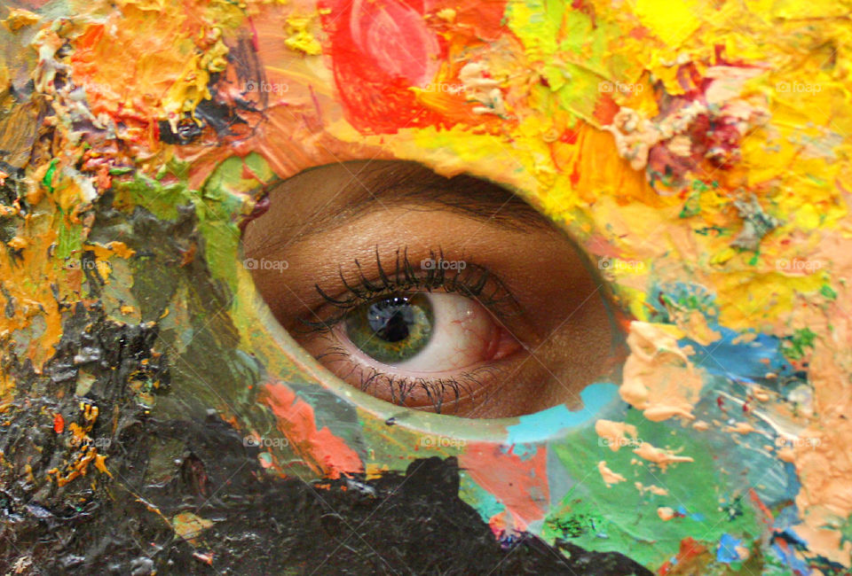 Artist's eye behind a colorful painting palette