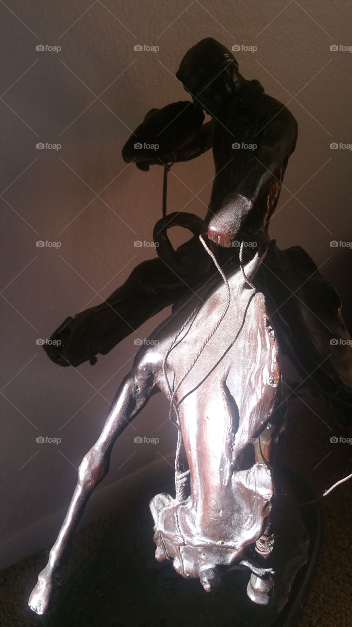 Bronze cowboy. a statue of a cowboy on a bucking bronco