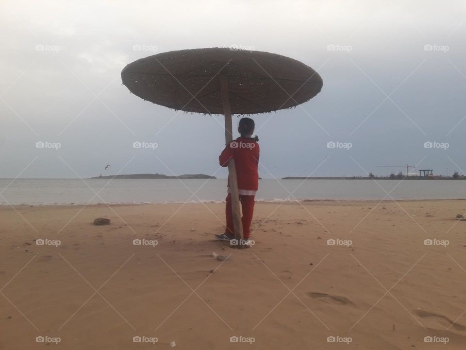 A young girl standing under umbrella.