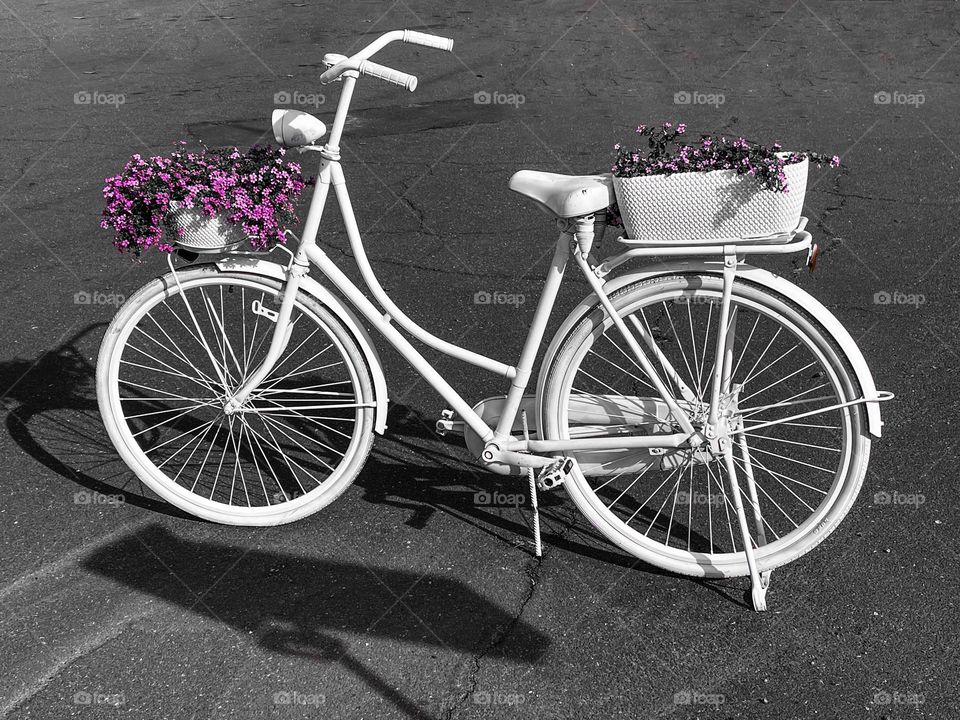 White bicycle with purple flowers at the street 