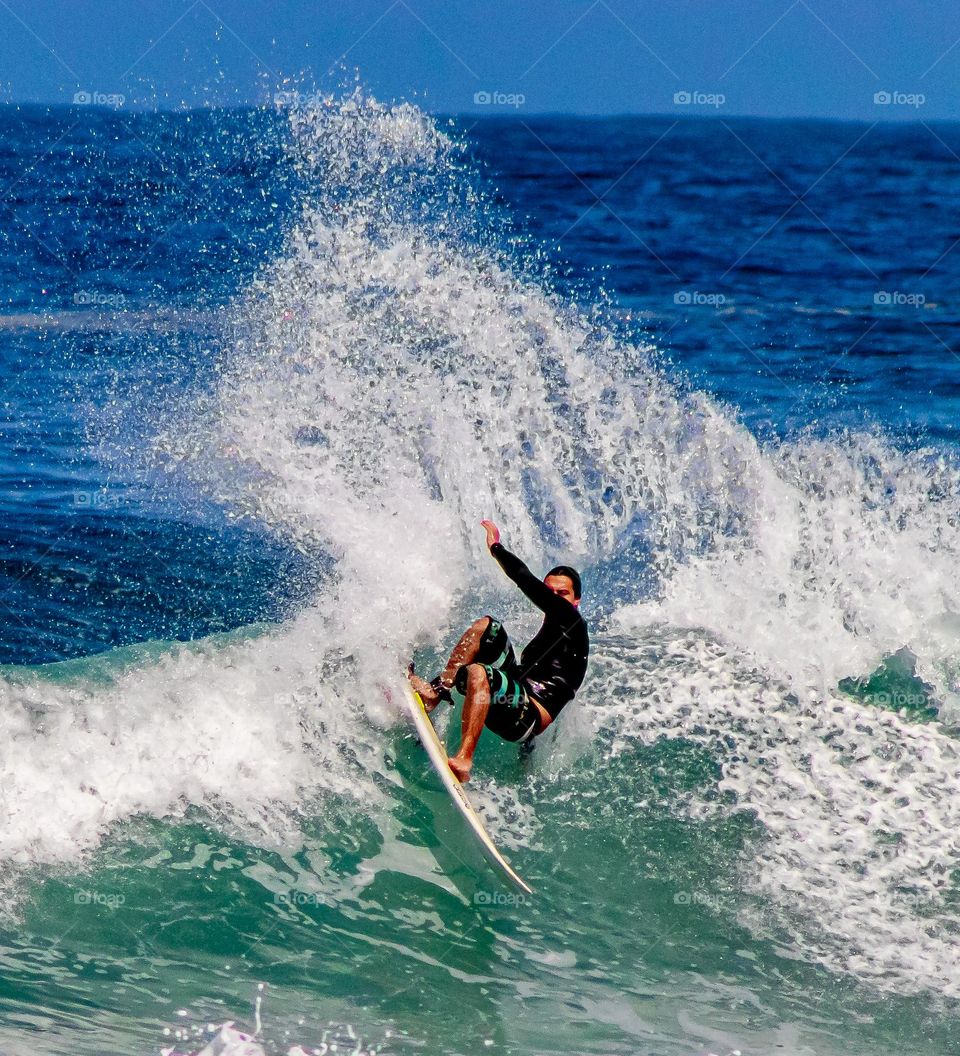 Surfista realizando manobra em praia brasileira.