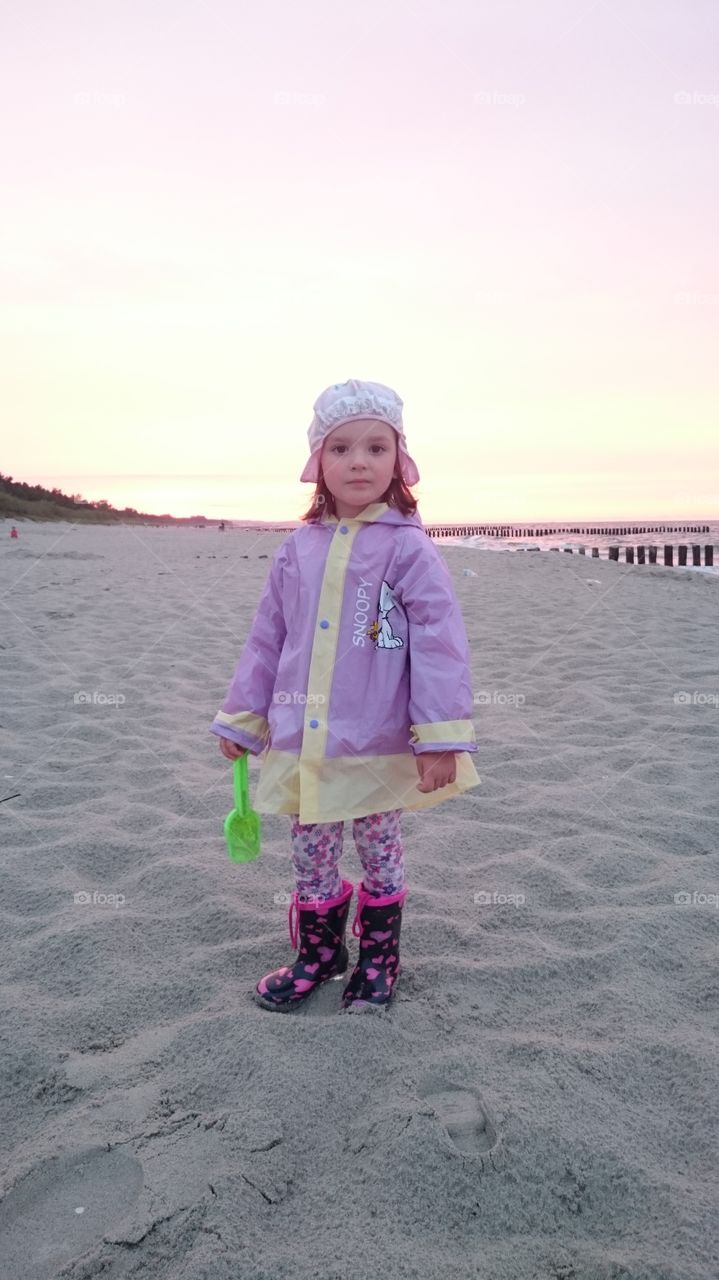 Cute girl standing on sandy beach