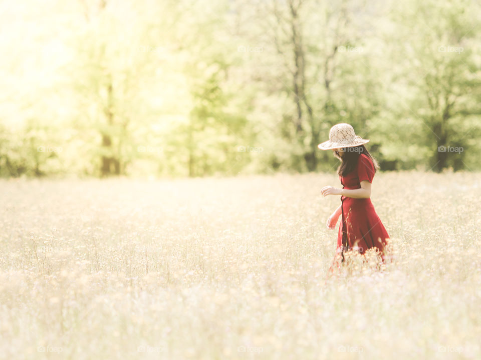 woman wearing red dress walk on the summer fields meadow