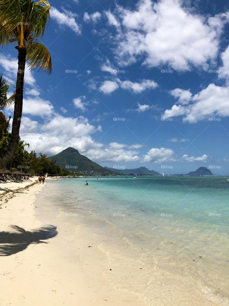 Coastal landscape view of Mauritius in bright sunshine with fluffy white clouds in a bright blue sky