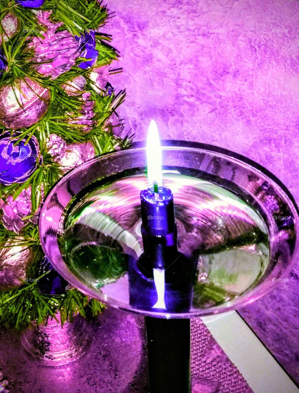 A purple Christmas candle with purple ornaments and background