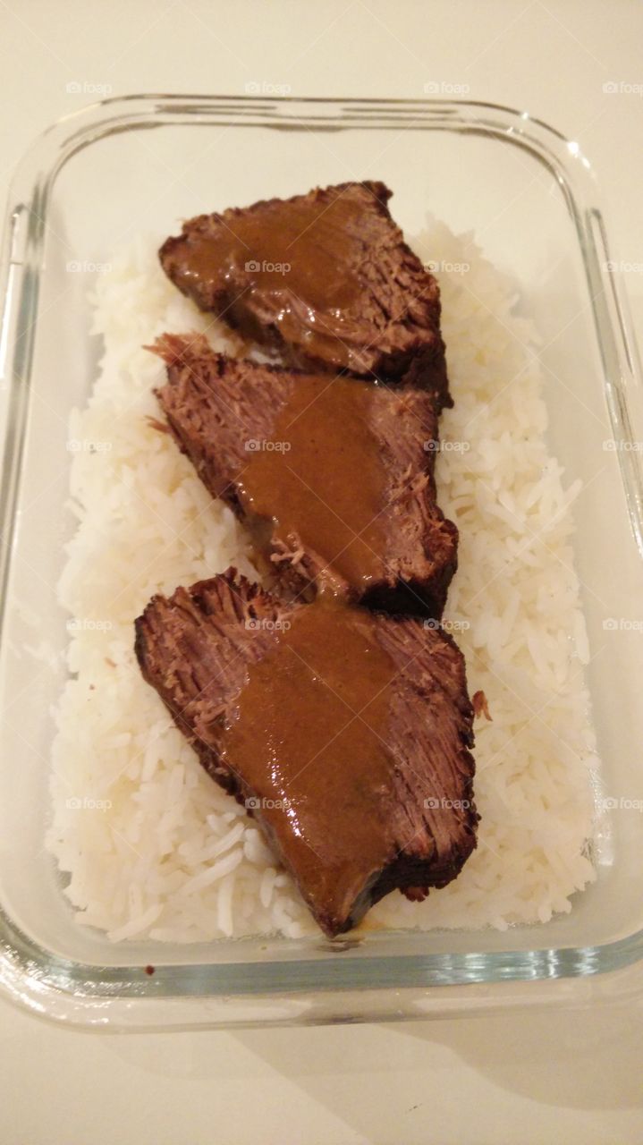 beef roast lunch prepping with gravy sauce on top on a bed of basmati rice