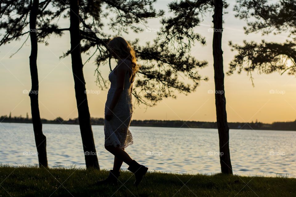 woman walking at sunset. woman walking at sunset beside the lake