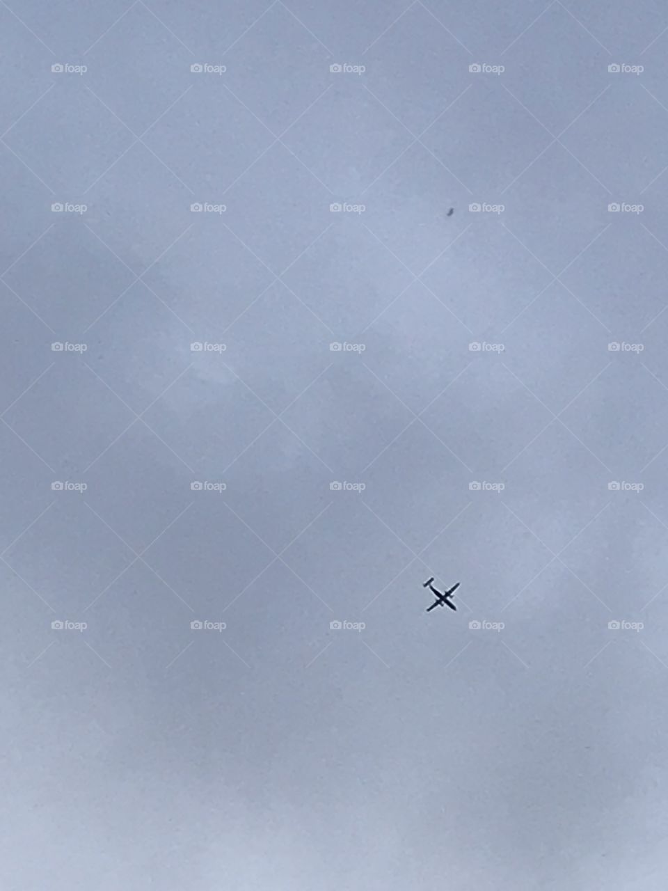 A Dash 8 q300 flying over in the foggy, grey skies. This turbo prop is owned by Widerøe (Widerøe) and is green and white.