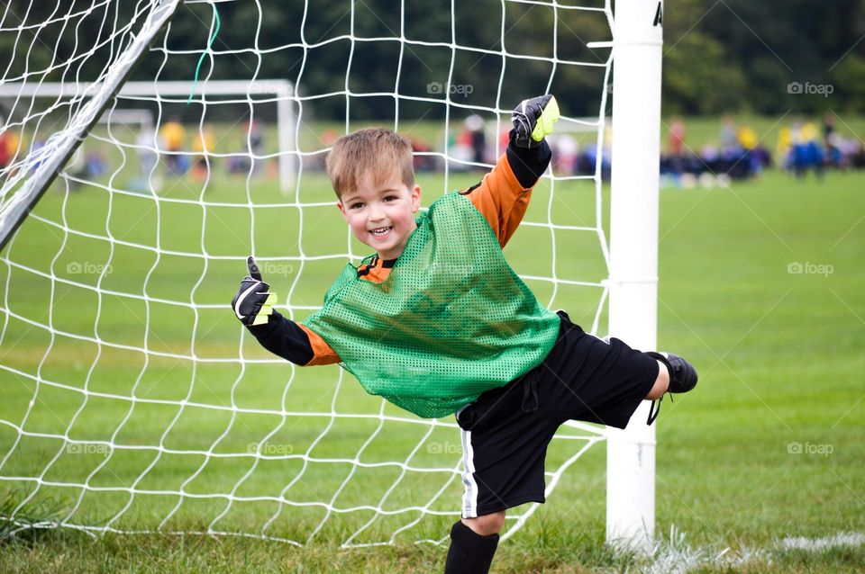 Young boy playing soccer at goalie position and giving a thumbs up 