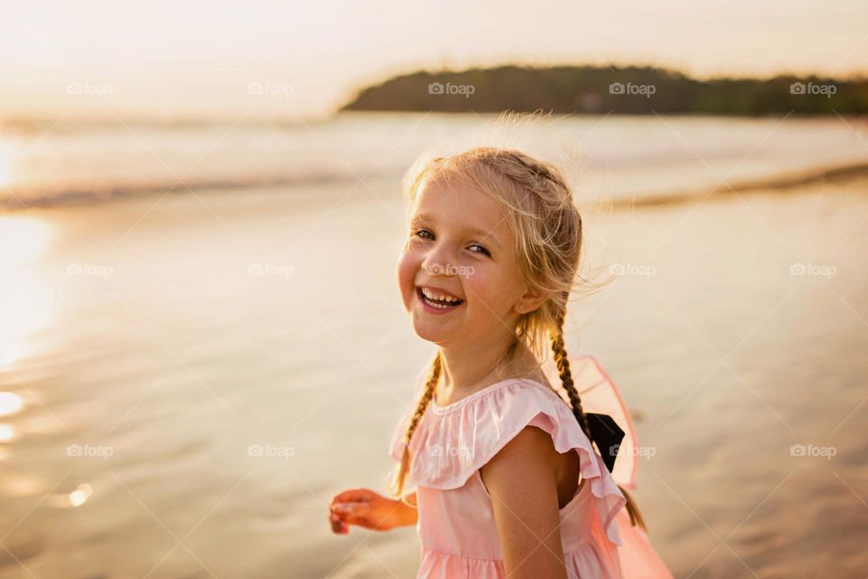 Candid portrait of happy little Caucasian girl on the beach 