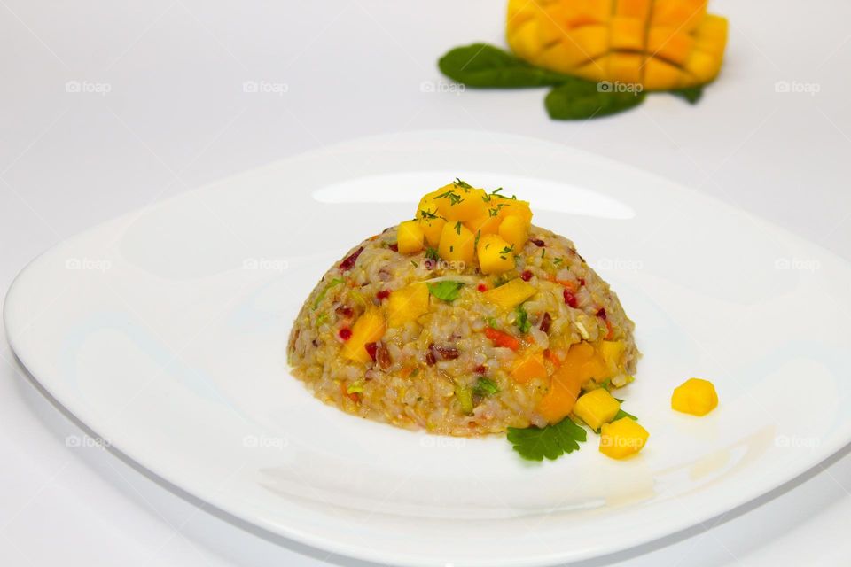 Integral rice with mango and vegetables on a white plate