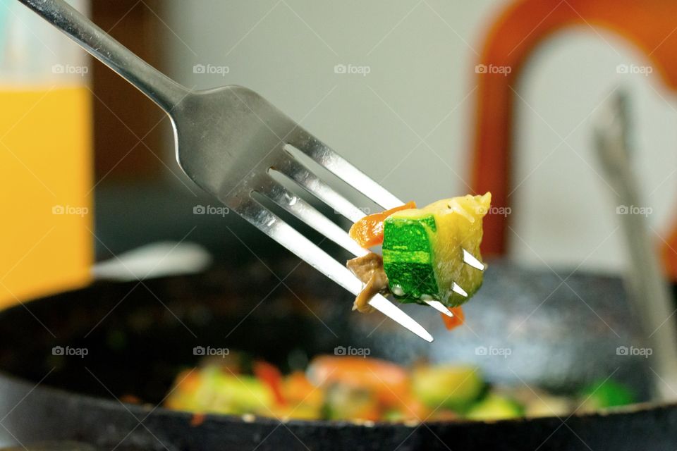Fork taking out A piece of vegetables from the skillet 