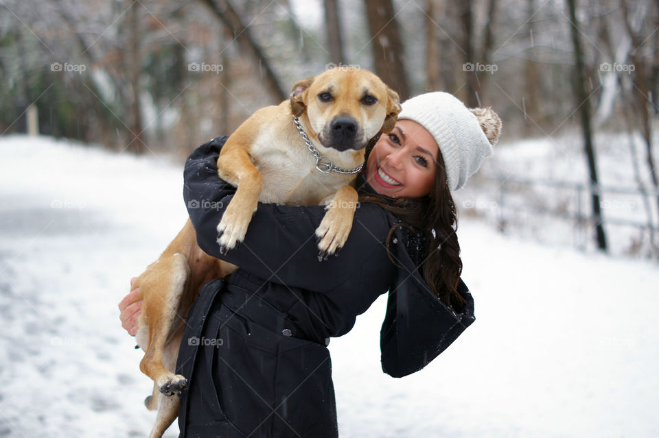 Young woman holding dog in winter