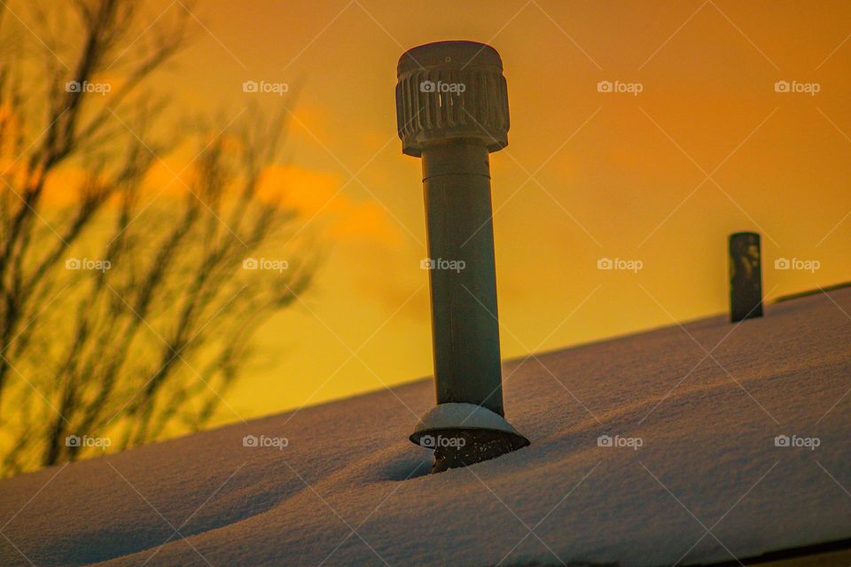 rooftop vent in the morning light on a snowy day