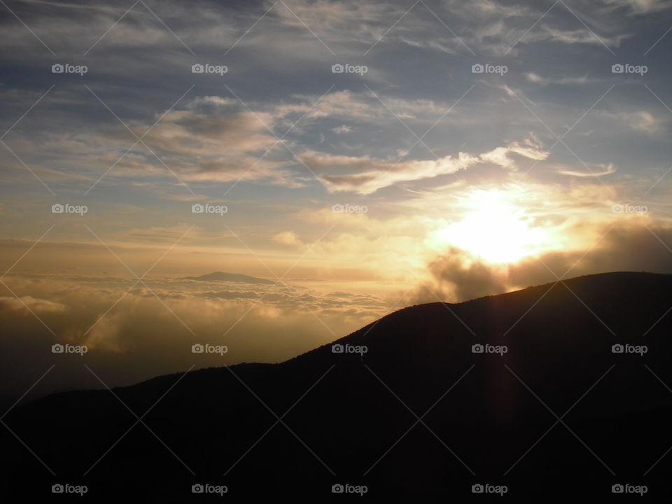 View of the sun setting into the clouds from Mauna Kea. 